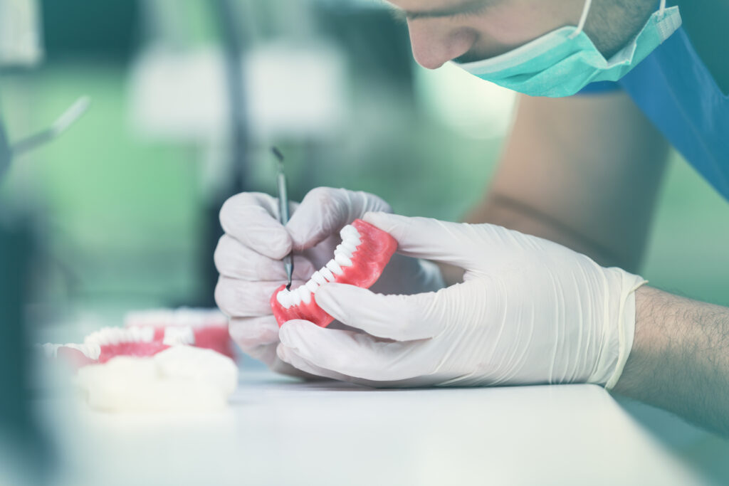 Getting To Know Your Dentures Better Dental prosthesis, dentures, prosthetics work. Dental students while working on the denture, false teeth, a study and a table with dental tools. Your Dentures